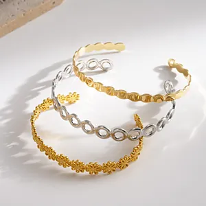Detailansicht der offenen Armreifen mit Blumenmuster und geometrischen Motiven in Gold und Silber.