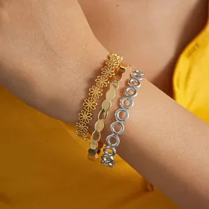 Nahaufnahme von drei stilvollen gold- und silbernen Armreifen an einem Handgelenk