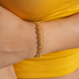 Detaillierte Nahaufnahme eines eleganten goldfarbenen Armbands mit Blumenmuster am Handgelenk.