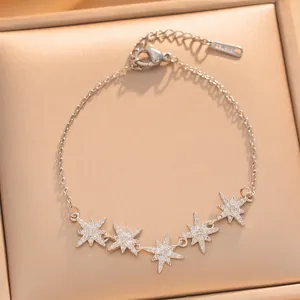 Vista detallada de dijes de estrellas de ocho puntas en plata con circonitas en la pulsera.