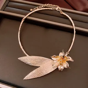 Dettaglio macro di collana a girocollo floreale in oro su vassoio di pelle marrone