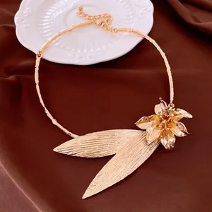 Primo piano di un'elegante collana girocollo dorata con fiori e foglie materici