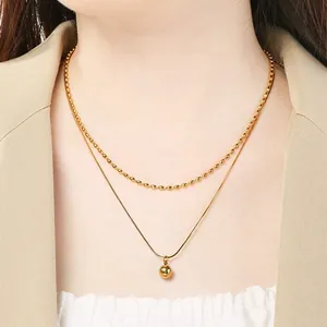 Élégant collier double couche en acier inoxydable doré avec un pendentif boule ronde.