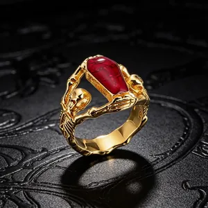 Close-up detail of a gothic style skeleton coffin ring with red resin inlay and gold plating