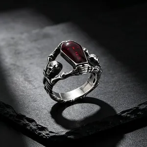 Detailed macro shot of a Gothic skull coffin ring featuring a deep red resin centerpiece.