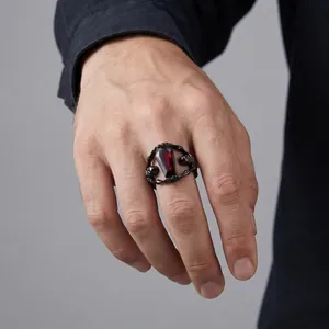 Close-up of a gothic skeleton coffin ring with a deep red gem on a hand model