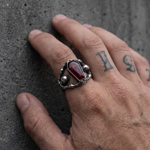 Gothic coffin-shaped ring with red resin and skull details on a tattooed hand