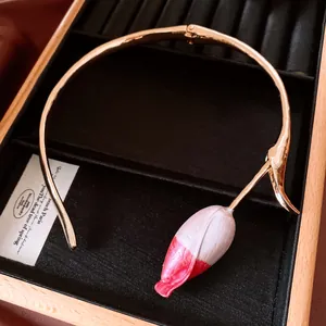 Primo piano di una collana girocollo dorata con ciondolo a bocciolo di tulipano rosa e bianco