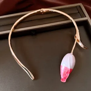 Elegante choker dorato con un delicato ciondolo a forma di bocciolo di fiore rosa dipinto.