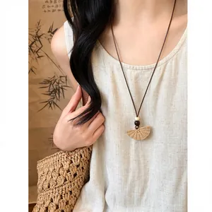 Close-up of a Bohemian fan-shaped woven pendant necklace on a vacation-style model