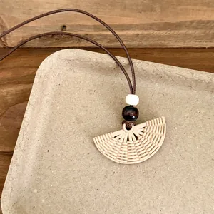Close-up of Bohemian woven fan-shaped pendant necklace with beads on brown cord