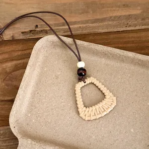 Detail view of Bohemian woven geometric pendant necklace with wooden bead accents.