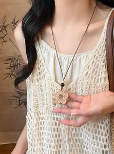 Close-up of bohemian woven flower pendant necklace with long adjustable cord on model