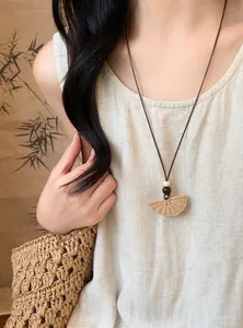 Close-up of a Bohemian long woven pendant necklace on a model wearing linen clothing