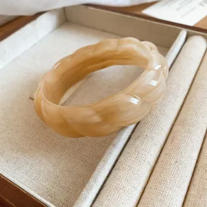 Close-up of a bohemian cream marbled acrylic bangle featuring a unique twisted wave texture