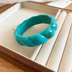 Close-up of a Bohemian turquoise marbled acrylic bangle with twisted texture in a display tray.