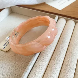 Close-up view of a bohemian peach acrylic bangle featuring unique marble swirl texture.