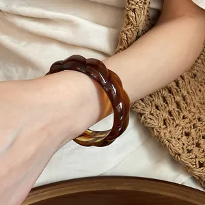 Close-up of a bohemian acrylic marbled twisted bangle worn on a wrist for a holiday look