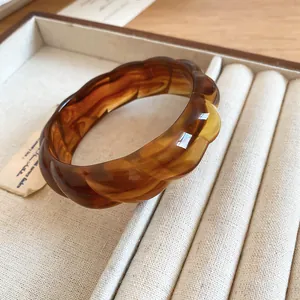 Close-up of a bohemian amber acrylic bangle with a unique twisted wavy texture.
