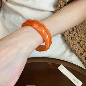 Detailed view of a bohemian orange marbled acrylic bangle with wavy texture on arm