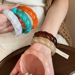 Close-up of bohemian acrylic bangles with marbled texture and twisted design