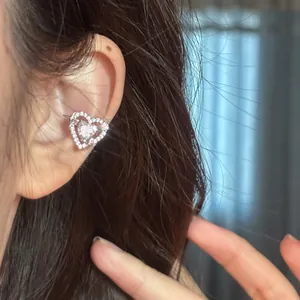 Detailed close-up of a sparkling heart-shaped ear cuff with cubic zirconia on an ear