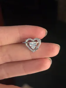 Detailed close-up of a sparkling heart zircon ear cuff with star motif on finger