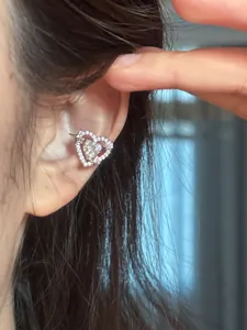 Detailed close-up showing a sparkling zircon heart ear cuff with star motif on a woman's ear