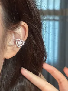 Detailed macro view of a sparkling heart-shaped zircon ear cuff worn on the ear.