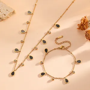 Detail view of gold titanium steel jewelry set with black water-drop pendants and gems.