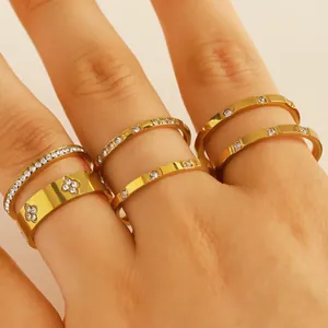 Detailed close-up view of stackable stainless steel gold rings with zircon stones on a hand