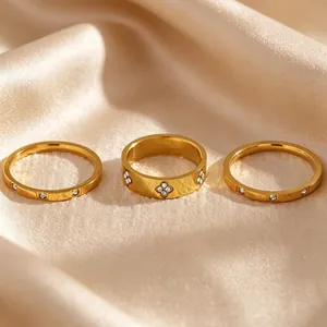 Close-up of three gold-plated stainless steel rings with zircon accents on silk