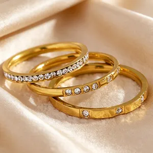 Detailed close-up of three stackable gold stainless steel rings with cubic zirconia on silk.
