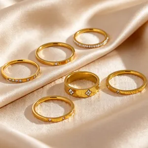 Macro view of gold stainless steel stacking rings with zircon on elegant champagne silk fabric