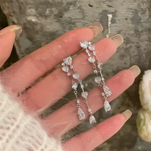 Close-up of sparkling heart-shaped tassel earrings with cubic zirconia drops