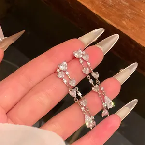 Close-up of silver heart fringe earrings with sparkling heart-shaped cubic zirconia stones