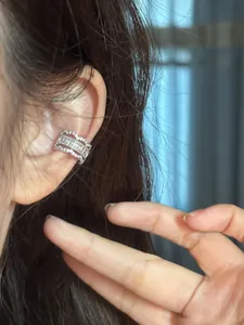 Gros plan d'un élégant ear cuff en zircon de style dentelle sur l'oreille de la mannequin