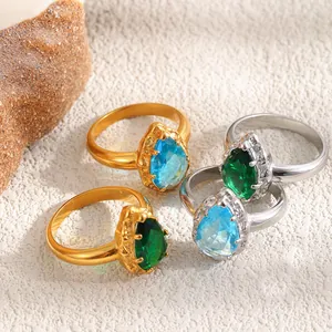 Detalle de circonitas en forma de pera verdes y azules en anillos bañados en oro y plata.