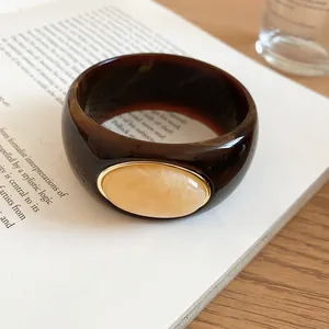 Close-up view of dark brown tortoiseshell acrylic bangle with cream marbled oval stone