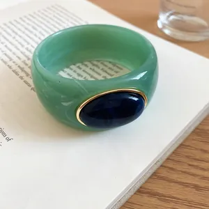 Close-up detail of the green marbled acrylic bangle with an elegant blue oval inlay design.