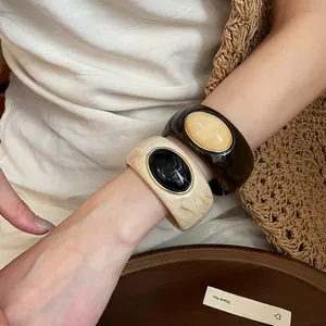 Close-up view of elegant acrylic marbled bangles in cream and brown on a model's wrist