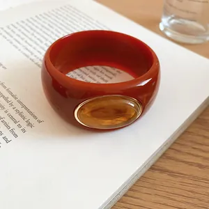Close-up of wide reddish-brown acrylic bangle with oval amber resin inset