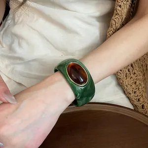 Detail view of a vintage green marbled acrylic bangle with a central amber resin stone.
