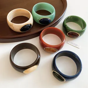 Detailed macro view of colorful acrylic bangles featuring marbled textures and oval inlays