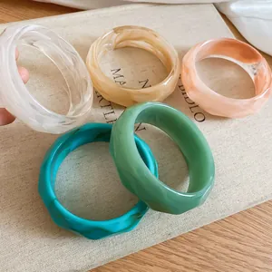 Primo piano di bracciali in resina ondulati irregolari in vari colori marmorizzati