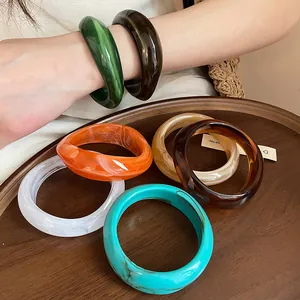 Detailed view of irregular geometric marbled acrylic bangles on a wood tray