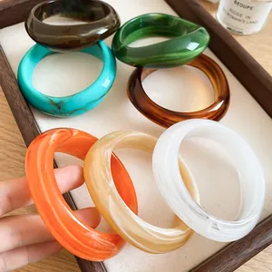 Detail of colorful irregular acrylic bangles with marbled texture on a display tray