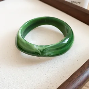 Detailed close-up of dark green marbled acrylic bracelet with irregular geometric shape
