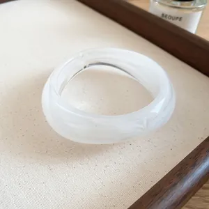 Macro detail of a modern irregular geometric white marbled acrylic bangle bracelet