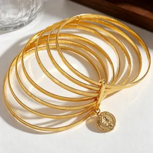 Detailed macro view of multi-layer gold frosted bangles with vintage coin charm